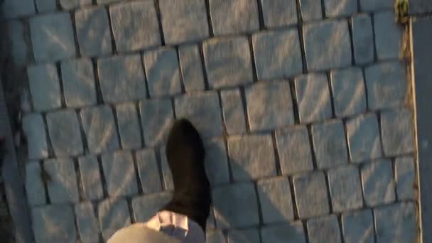 Вид сверху женских ног в замшевых сапогах и плиссированной юбке, идущих по тротуару — стоковое видео