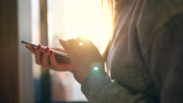 Kvinnliga händer med smartphone mot en suddig stadsbilden i solnedgången — Stockvideo