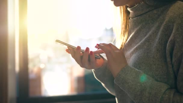 Mani femminili utilizzando lo smartphone contro un paesaggio urbano sfocato al sole al tramonto — Video Stock