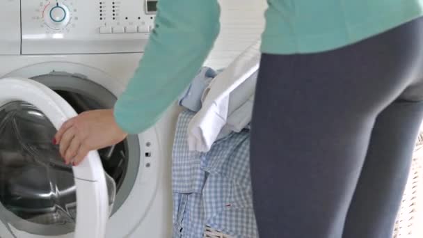 Женщина загружает белье в стиральную машину — стоковое видео