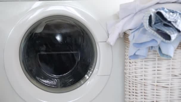 Laundry is washed in the washing machine, and clean things are on the basket nearby. — Stock Video