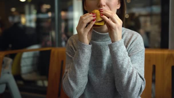 Frau isst Hamburger in Café — Stockvideo