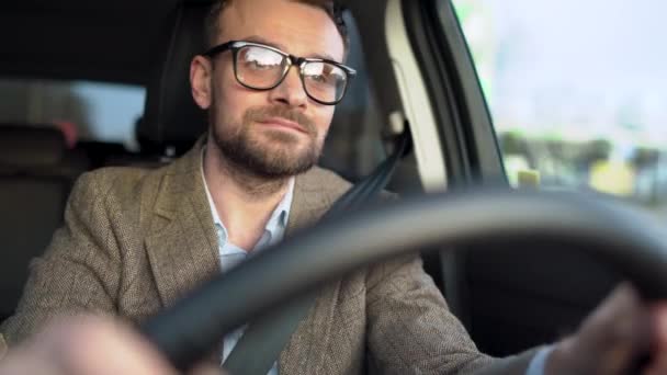 Homem barbudo satisfeito em óculos dirigindo um carro na rua com o tempo ensolarado — Vídeo de Stock
