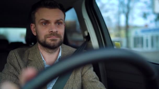 Soddisfatto uomo barbuto alla guida di una macchina in fondo alla strada con tempo soleggiato — Video Stock
