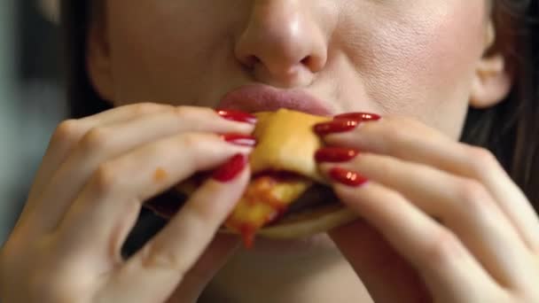 Woman eats a hamburger in a cafe — Stock Video