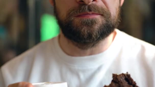 L'uomo mangia biscotti con gocce di cioccolato e beve caffè in un caffè — Video Stock