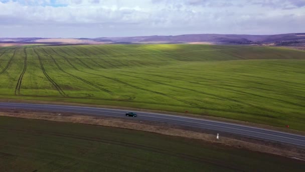 Vue de la hauteur sur le paysage rural : champ vert et nuages pittoresques dans le ciel et la route entre deux champs — Video