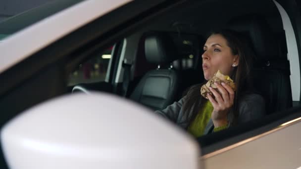 Mujer comiendo sándwich sentado en el coche en el aparcamiento. Concepto de una vida ocupada moderna — Vídeos de Stock