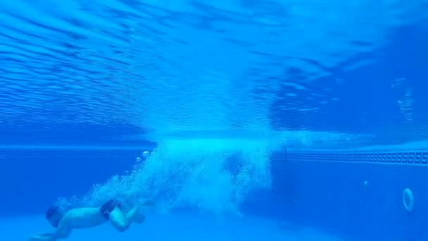 Tir sous-marin comme un homme plonge dans la piscine et nage sous l'eau. Mouvement lent — Video