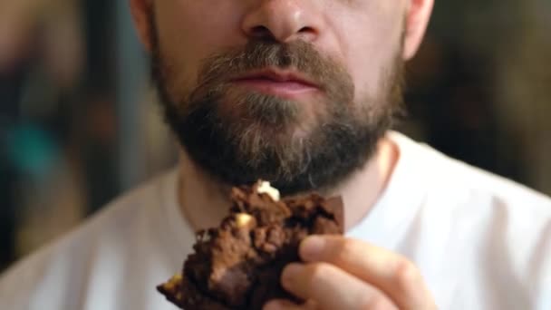 Homem come um biscoito de chocolate em um café — Vídeo de Stock