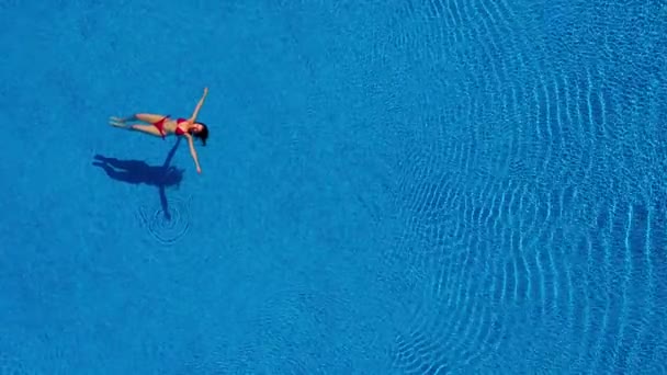 从顶部看，一个穿红色泳衣的女人在游泳池里游回泳 — 图库视频影像