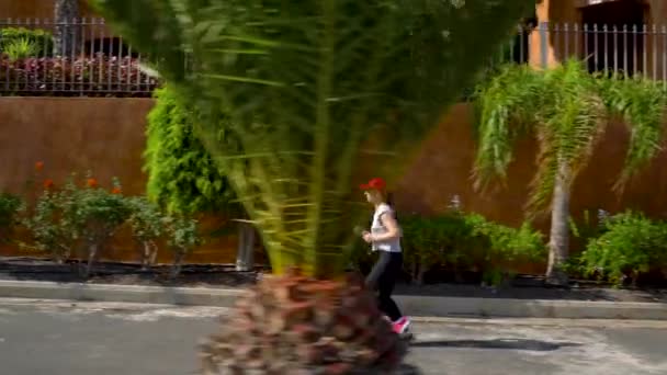 La mujer corre por la calle entre las palmeras. Vida activa saludable — Vídeo de stock