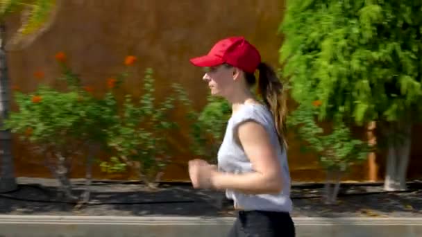 Kobieta biegnie w dół ulicy wśród drzew palmowych. Zdrowy, aktywny styl życia — Wideo stockowe