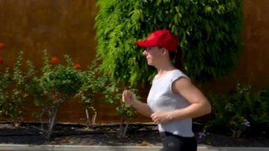 Kadın sokakta palmiye ağaçları arasında koşuyor. Sağlıklı aktif yaşam tarzı. Yavaş hareket