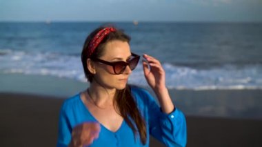 Siyah bir volkanik plajda güzel mavi elbiseli bir kadının portresi. Yavaş çekim