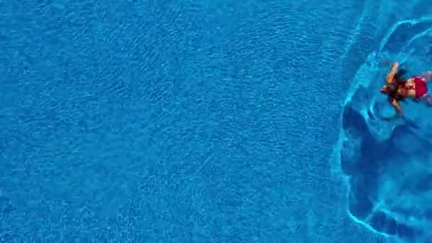 Blick von oben, als eine Frau im roten Badeanzug im Pool schwimmt — Stockvideo