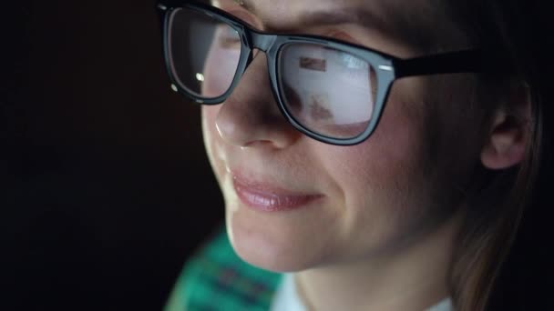 Mujer con gafas mirando en el monitor y navegando por Internet. La pantalla del monitor se refleja en las gafas — Vídeos de Stock