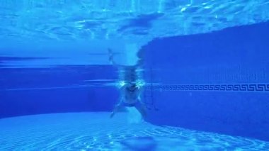 Bir adam havuzda su altında yüzerken sualtı çekim