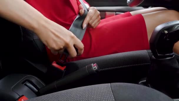 Woman in red dress fastening car safety seat belt while sitting inside of vehicle before driving — Stock Video