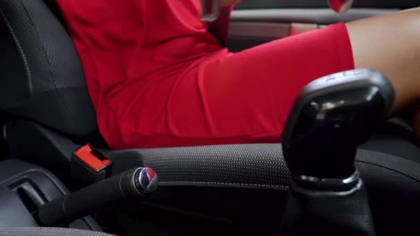 Woman in red dress fastening car safety seat belt while sitting inside of vehicle before driving — Stock Video