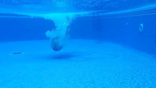 Onderwater schieten als een man duikt als een bom in het zwembad en zwemt onder het water. Slow Motion — Stockvideo