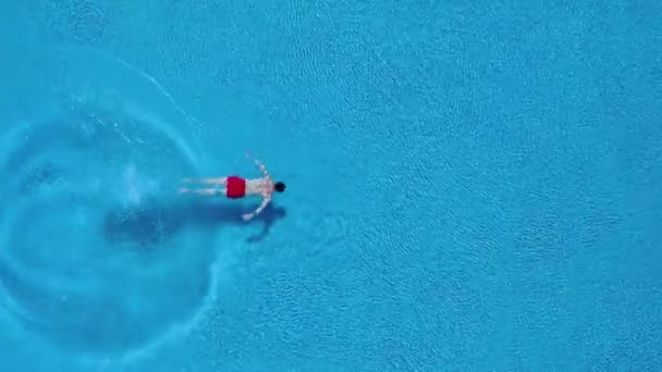 Blick von oben, als ein Mann in den Pool eintaucht und unter Wasser schwimmt — Stockvideo