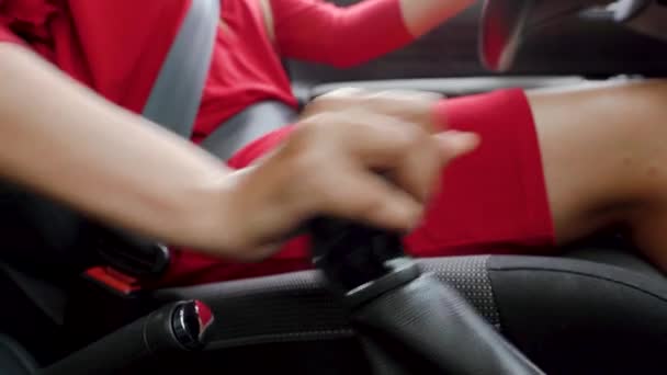 Kvinna i röd klänning sitter inne i fordonet och kontrollerar växellådan i en bil innan du kör — Stockvideo