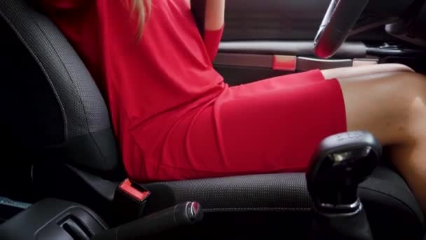 Mujer con vestido rojo sujetando el cinturón de seguridad del coche mientras está sentado dentro del vehículo antes de conducir — Vídeos de Stock