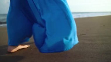 Siyah bir volkanik plaj boyunca yürüyüş güzel mavi elbise bir kadının bacaklar