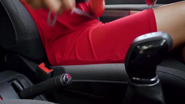 Mujer con vestido rojo sujetando el cinturón de seguridad del coche mientras está sentado dentro del vehículo antes de conducir — Vídeo de stock