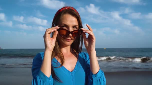 Ritratto di una donna ingannevole in un bel vestito blu su una spiaggia vulcanica nera — Video Stock