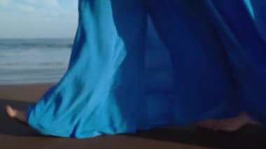 Siyah volkanik plaj boyunca yürüyen güzel mavi elbiseli kadın