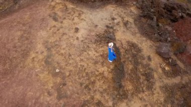 Güzel mavi elbise ve şapka lı bir kadının havadan görünümü, Atlantik Okyanusu kıyılarındaki bir koruma alanında bir dağın tepesinde duruyor. Tenerife, Kanarya Adaları, İspanya