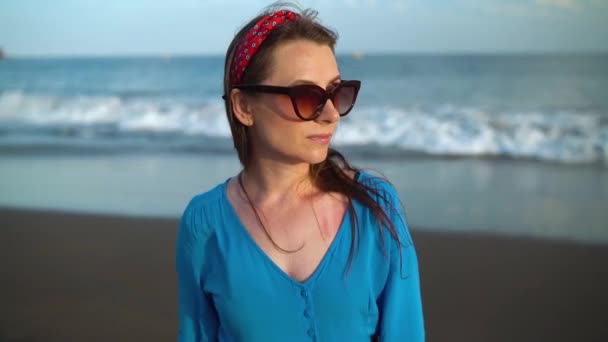 Portret kobiety w pięknej niebieskiej sukni na czarnej wulkanicznej plaży — Wideo stockowe