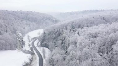 Bir peri kış manzara havadan görünümü - kışın karla kaplı bir ormanda bir yol boyunca bir araba sürmek
