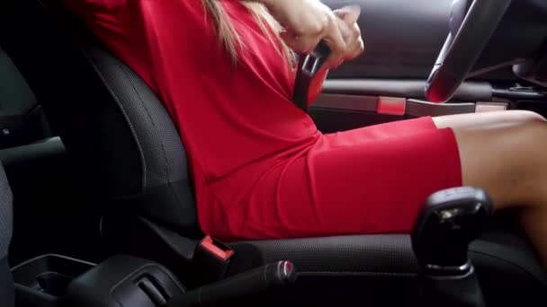 Vrouw in rode jurk bevestiging auto veiligheidsgordel terwijl zittend in het voertuig voor het rijden — Stockvideo