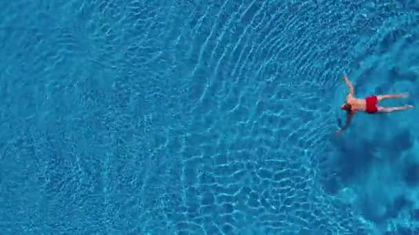 Vista aerea dell'uomo in pantaloncini rossi nuota in piscina — Video Stock