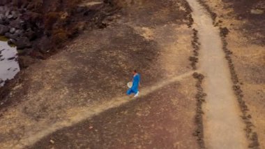 Güzel mavi elbiseli bir kadının havadan görünümü ve Atlantik Okyanusu kıyılarında bir koruma alanında bir dağın tepesine hatwalking. Tenerife, Kanarya Adaları, İspanya