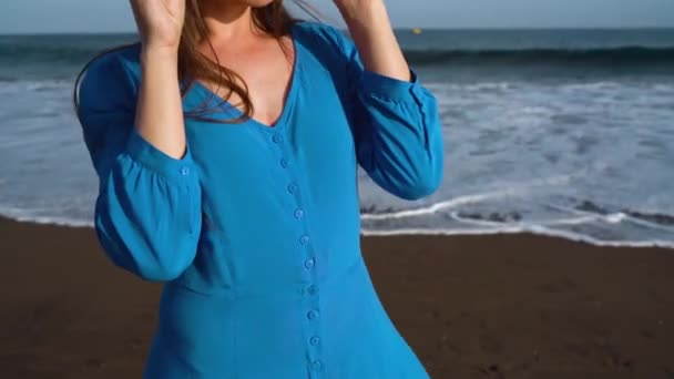 Retrato de una mujer en un hermoso vestido azul en una playa volcánica negra — Vídeo de stock