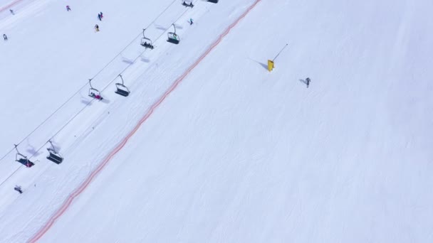 Pista de esquí - telesilla, esquiadores y snowboarders bajando. Vista aérea — Vídeo de stock
