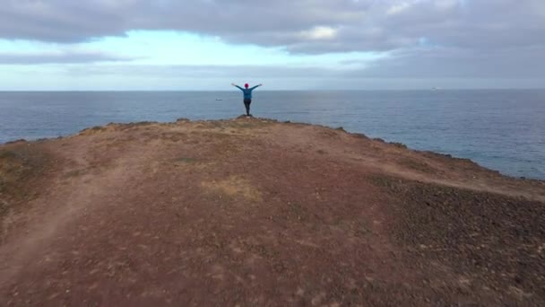Repül át nő sportruházat után jogging áll a tetején egy szikla, és élvezi a tájat, a természetvédelmi terület partján az Atlanti-óceánon. Tenerife, Kanári-szigetek, Spanyolország — Stock videók