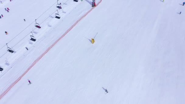 Лыжный склон - лыжный подъемник, лыжники и сноубордисты спускаются вниз. Вид с воздуха — стоковое видео