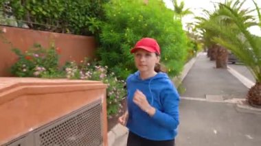 Tropik sokak arasında cadde boyunca koşan bir kadın. Yavaş çekim