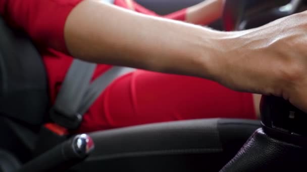 Close-up da mulher motorista em um vestido vermelho prende seu cinto de segurança, muda de engrenagem e começa a se mover — Vídeo de Stock