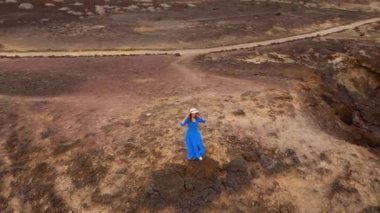 Güzel mavi elbise ve şapka lı bir kadının havadan görünümü, Atlantik Okyanusu kıyılarındaki bir koruma alanında bir dağın tepesinde duruyor. Tenerife, Kanarya Adaları, İspanya