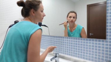 Banyo aynası önünde makyaj fırçası ile Pretty kadın toz yüz