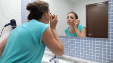 Banyo aynası önünde kirpik makyaj ı için siyah maskara uygulayan güzel kadın