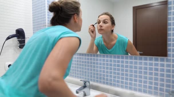 Mooie vrouw het toepassen van zwarte Mascara voor wimpers make-up in de voorkant van de badkamerspiegel — Stockvideo