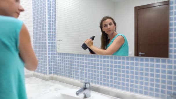 Красива жінка дме волосся перед дзеркалом у ванній — стокове відео