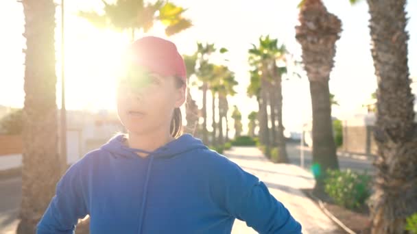 Kvinnan stannar medan jogging för att kontrollera data i Smart Watch-programmet, vilar och fortsätter att köra — Stockvideo